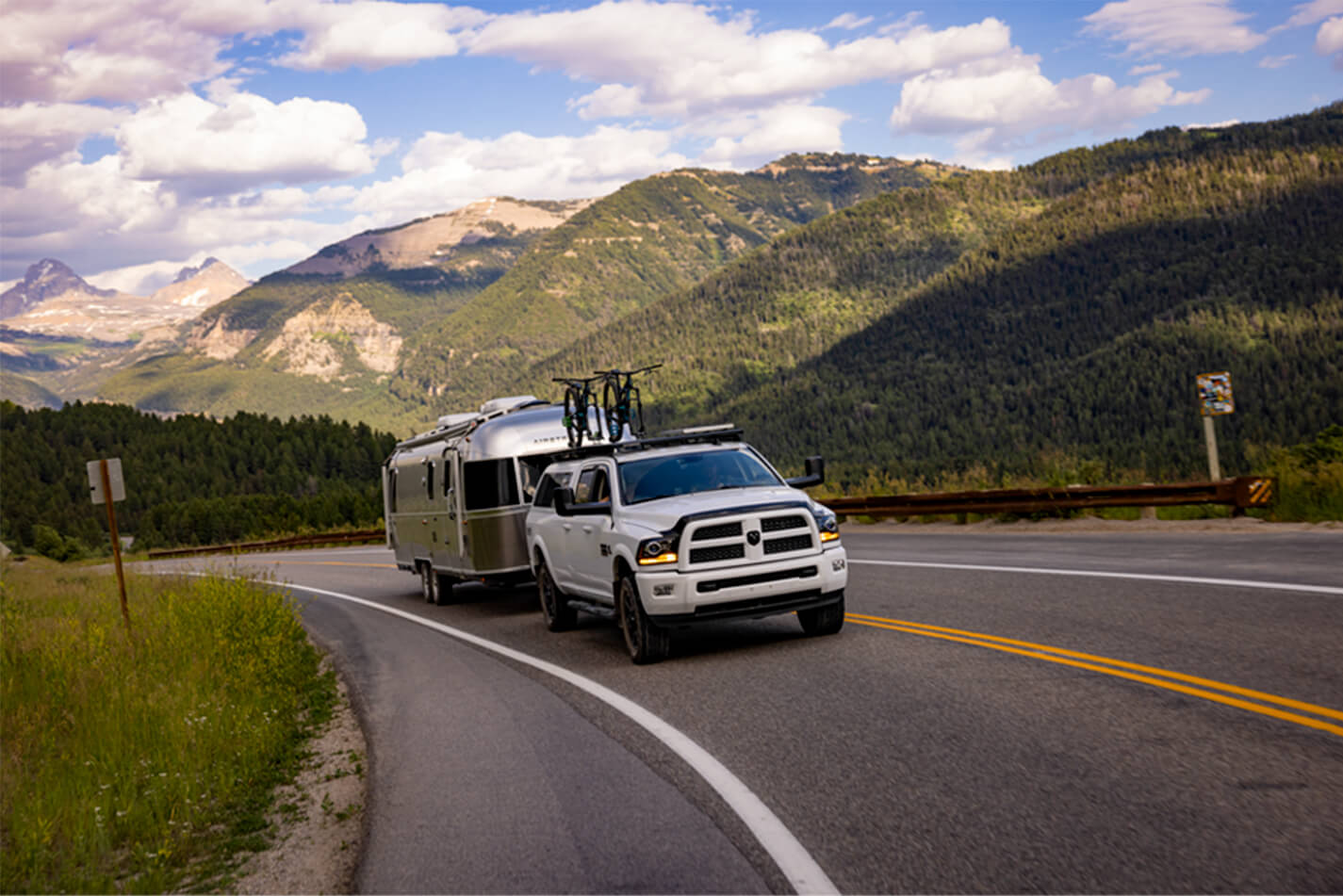Pickup truck towing a travel trailer through the mountains